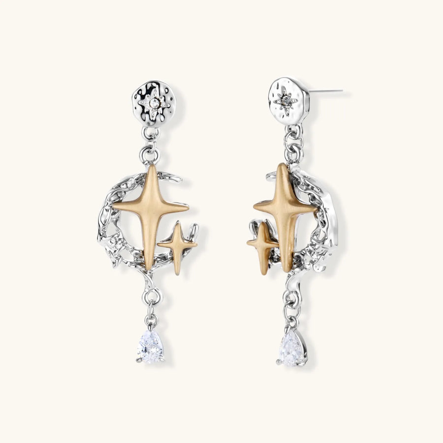 Two-tone star earrings with gold celestial motifs, silver chains, and clear crystal droplets on white background.