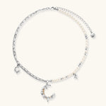 Silver-toned crescent moon pendant with star accents on pearl and chain necklace against white background.