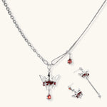 Silver-tone crown pendant with red zirconia stones and matching asymmetrical earrings on cream background