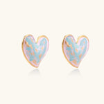 Heart-shaped stud earrings with swirled turquoise and pink enamel in gold-plated frames on cream background