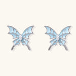 Long silver-tone earrings with powder blue enamel butterfly studs and flowing chain tassels on cream background