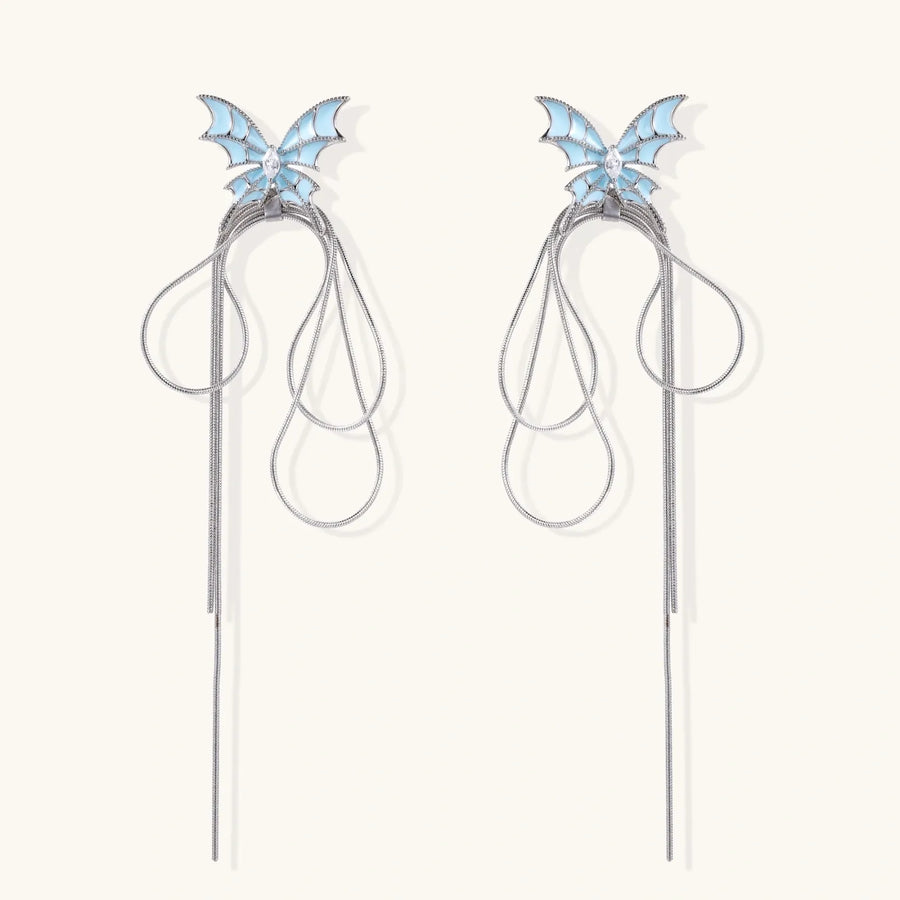 Long silver-tone earrings with powder blue enamel butterfly studs and flowing chain tassels on cream background