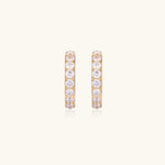 Gold pavé hoop earrings with two freshwater pearls nestled inside the curved design, featuring crystal-studded outer edge.