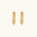 Gold-toned hoop earrings with hammered dimpled texture and post closure on cream background