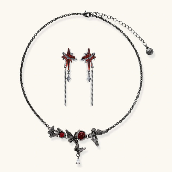 Gothic jewelry set with red resin cross pendants wrapped in dark metal chains on cream background.