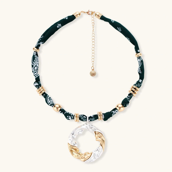 Adjustable necklace with black paisley fabric cord, gold metal spacers, and clear twisted pendant on cream background
