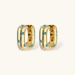 Gold-plated huggie hoop earrings with blue star inlays and textured surface, shown against white background.