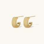 Small gold huggie earrings with matte finish, 14mm diameter, shown against cream background for everyday elegance.
